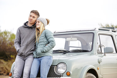 Romantisches junges Paar lehnt an einem Auto am Strand - CUF14348