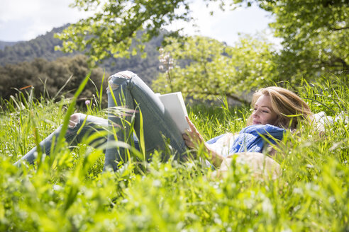 Woman lying on grass reading - CUF14423