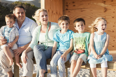 Familie am Strand schaut lächelnd in die Kamera - CUF14437