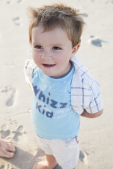 Boy on beach, hands behind back looking away smiling - CUF14438