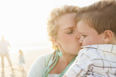 Mother on beach kissing son on cheek - CUF14442