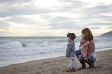 Mother and daughter on beach looking at ocean - CUF14446