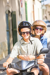 Junges Paar fährt mit dem Moped durch ein Dorf, Mallorca, Spanien - CUF14481