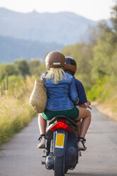 Rear view of young couple riding moped on rural road, Majorca, Spain - CUF14484