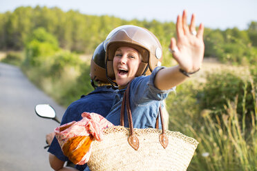 Young woman riding pillion on rural road waving, Majorca, Spain - CUF14486