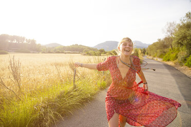 Junge Frau läuft und lacht auf einer Landstraße, Mallorca, Spanien - CUF14487