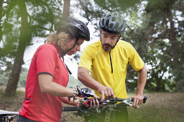 Mountainbike-Paar prüft Fahrradlenker im Wald - CUF14492