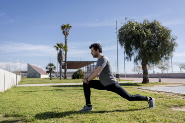 Sportive man stretching on a meadow - MAUF01398