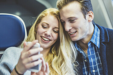 Junges Paar liest Smartphone-Texte im Zugwaggon - CUF14610