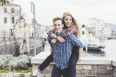 Portrait of young man giving girlfriend a piggyback, Lake Como, Italy - CUF14613