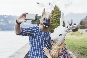 Ein Paar mit Pferde- und Hasenmasken macht ein Smartphone-Selfie, Comer See, Italien - CUF14615