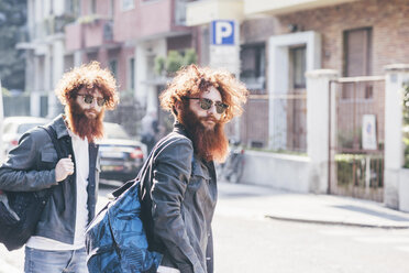 Young male hipster twins with red hair and beards strolling on road - CUF14665