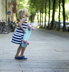 Glückliches kleines Mädchen mit Skateboard auf dem Bürgersteig - BEF00106