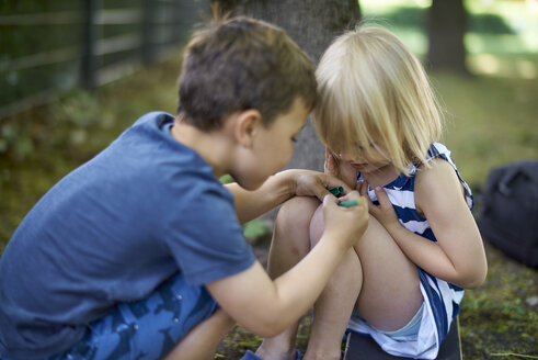 Junge malt auf dem Knie seiner kleinen Schwester - BEF00108