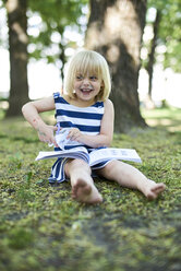Portrait of laughing little girl with painted face sitting on ground in nature - BEF00112