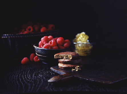 Luxuriöse schokoladenüberzogene Kekse mit Himbeer- und Honiggeschmack und Himbeeren auf dem Vintage-Tisch, unaufdringlich - CUF14696