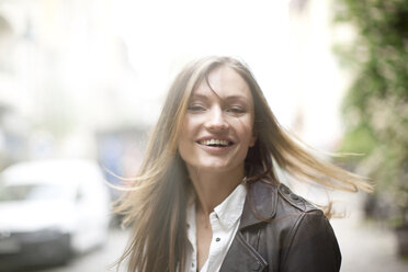 Carefree woman with long flyaway hair on city street - CUF14774