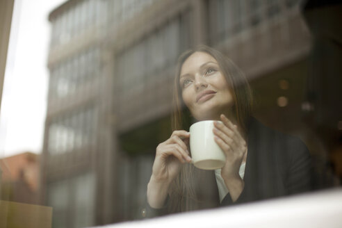 Businesswoman gazing through cafe window, Freiburg, Germany - CUF14776