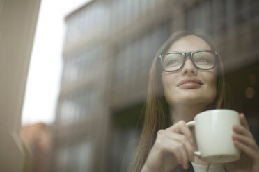 Businesswoman with coffee cup at cafe window, Freiburg, Germany - CUF14777