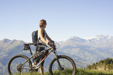 Female mountain biker looking out at mountain landscape, Aosta Valley, Aosta, Italy - CUF14842