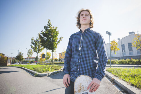 Porträt eines jungen männlichen Skateboarders auf dem Bürgersteig - CUF14845
