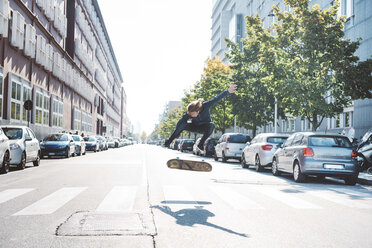 Junger männlicher Skateboarder, der auf einem Fußgängerüberweg mitten in der Luft springt - CUF14848