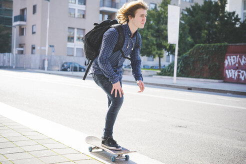 Junger männlicher Skateboarder, der auf dem Bürgersteig Skateboard fährt - CUF14852