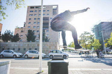 Junger männlicher Skateboarder fährt mit dem Skateboard über einen Mülleimer auf dem Bürgersteig - CUF14853