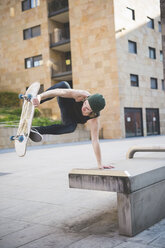Junger männlicher Skateboarder, der einen Balance-Skateboard-Trick auf dem Sitz einer städtischen Halle ausführt - CUF14857