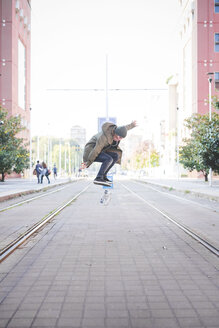 Junger männlicher Skateboarder beim Skateboard-Sprung auf der Straßenbahn - CUF14861