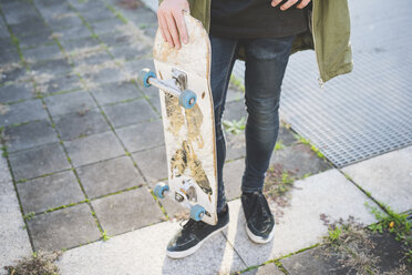 Waist down view of young male urban skateboarder standing on sidewalk - CUF14867