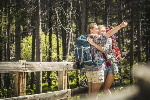 Teenager-Mädchen und junge Wanderin umarmen sich auf einer Fußgängerbrücke für ein Selfie, Red Lodge, Montana, USA - CUF14894