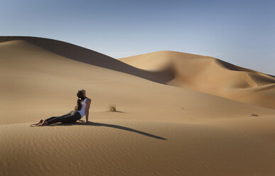 Junge Frau übt Yoga auf einer Sanddüne in der Wüste, Abu Dhabi, Emirat Abu Dhabi, VAE - CUF14974