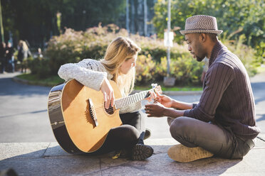 Ehepaar lernt im Park Gitarre zu spielen - CUF14988