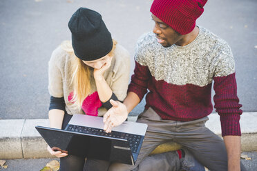 Couple using laptop on pavement - CUF15002