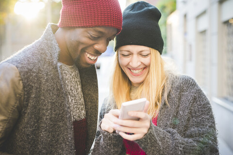 Paar lächelt über Nachricht auf Smartphone, lizenzfreies Stockfoto