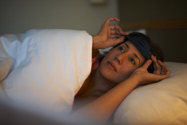 Reife Frau setzt nachts im Hotelbett eine Augenmaske auf - CUF15028