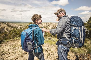 Wandernder Vater und jugendlicher Sohn zeigen auf die Landschaft, Cody, Wyoming, USA - CUF15048