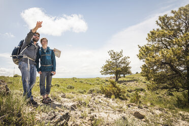 Hiking father and teenage son with map pointing over landscape, Cody, Wyoming, USA - CUF15049