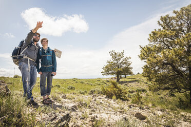 Wandernder Vater und Sohn im Teenageralter mit Karte, die über die Landschaft zeigt, Cody, Wyoming, USA - CUF15049