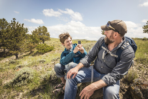 Teenage boy photographing father on hiking trip, Cody, Wyoming, USA stock photo