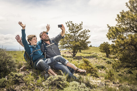 Father and teenage son waving for selfie on hiking trip, Cody, Wyoming, USA stock photo