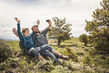 Father and teenage son waving for selfie on hiking trip, Cody, Wyoming, USA - CUF15057