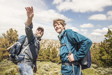 Vater und Sohn im Teenageralter weisen beim Wandern auf die Landschaft hin, Cody, Wyoming, USA - CUF15062