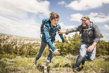 Vater und Sohn im Teenageralter jagen sich gegenseitig auf einem Wanderausflug, Cody, Wyoming, USA - CUF15063