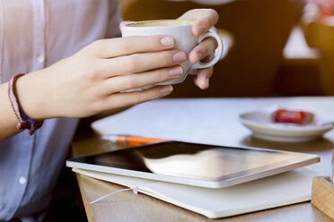 Hände einer jungen Frau, die eine Kaffeetasse hält und ein digitales Tablet benutzt - CUF15091