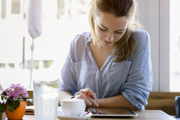 Young woman in cafe writing, looking at camera smiling - CUF15093