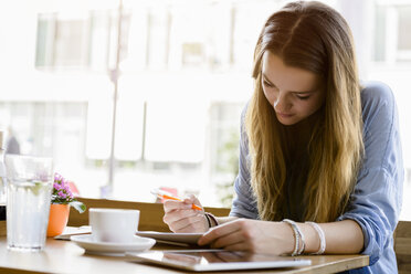 Young woman in cafe looking down writing - CUF15098