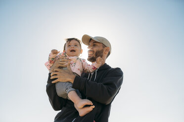 Lachender Vater hält kleines Mädchen im Gegenlicht - GEMF02033