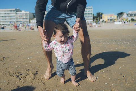 Frankreich, La Baule, kleines Mädchen, das mit seinem Vater am Strand laufen lernt, lizenzfreies Stockfoto